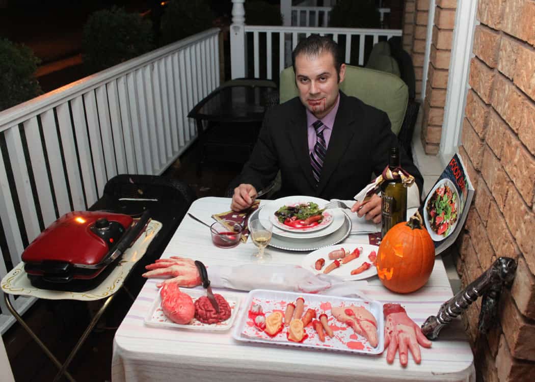 man dressed as Hannibal the Cannibal sitting at dinner table